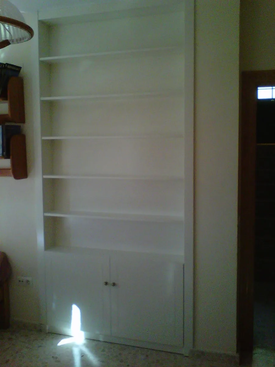 Librería blanca empotrada en un hueco de la pared, con puertas abajo