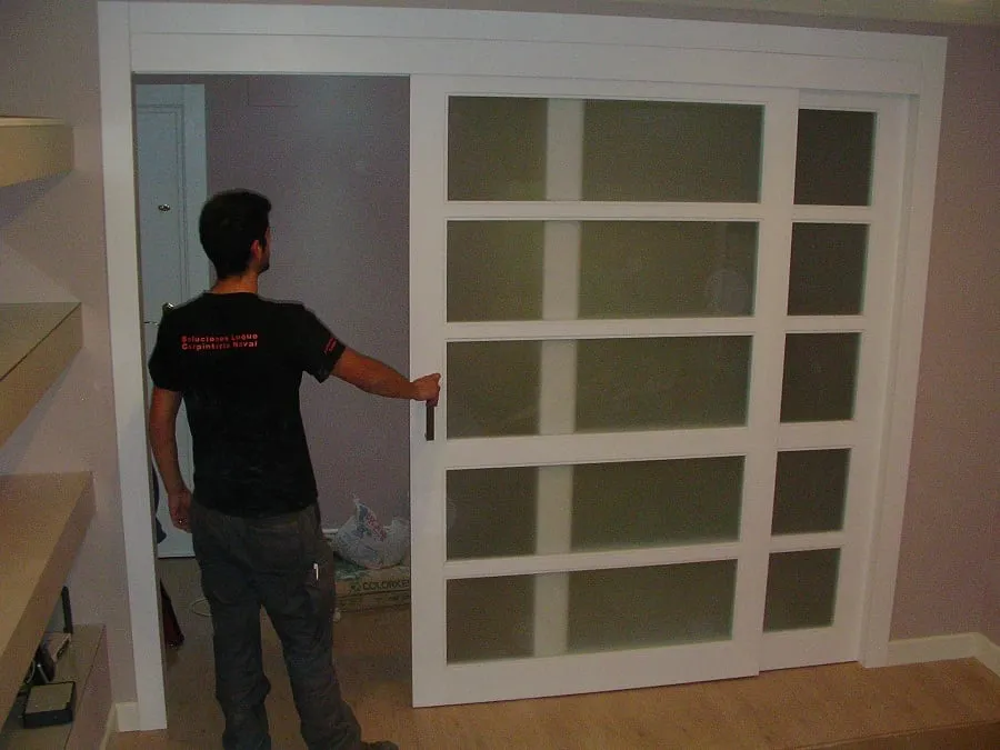 Puerta corredera blanca con cuarterones de cristal que separa dos estancias