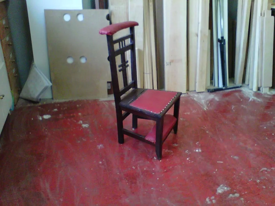 Silla reclinatorio de madera oscura y tapizado rojo, cerrada