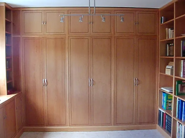 Ropero de cerezo de 6 puertas con altillo, junto a una librería