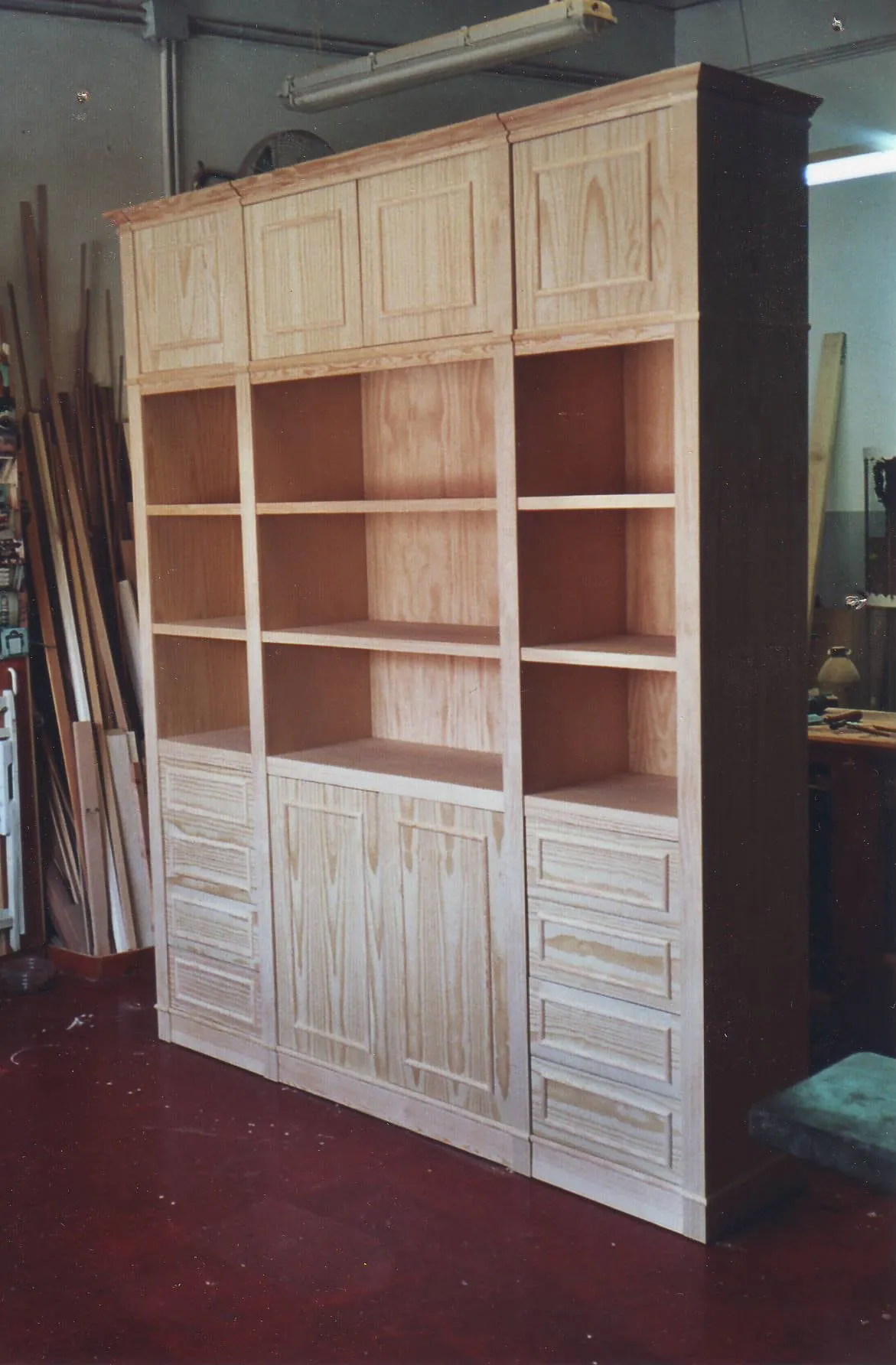 Mueble de madera en crudo con altillo, baldas y cajones, en el taller